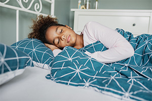 a school aged child sleeping in their bed