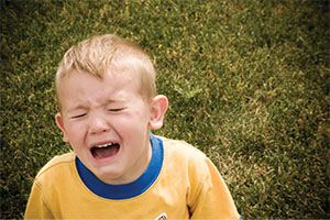 A boy sitting and crying on grass