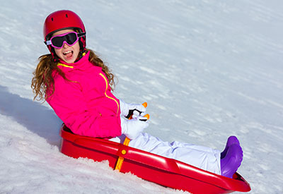 A girl sleds down a snowy hill