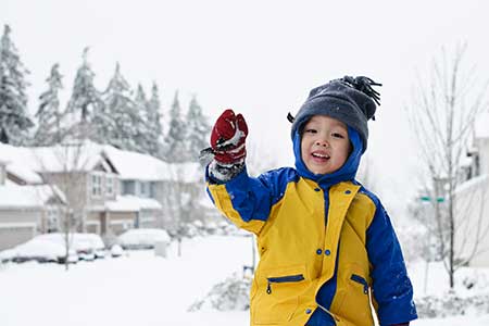 A child in winter gear holds a snowball