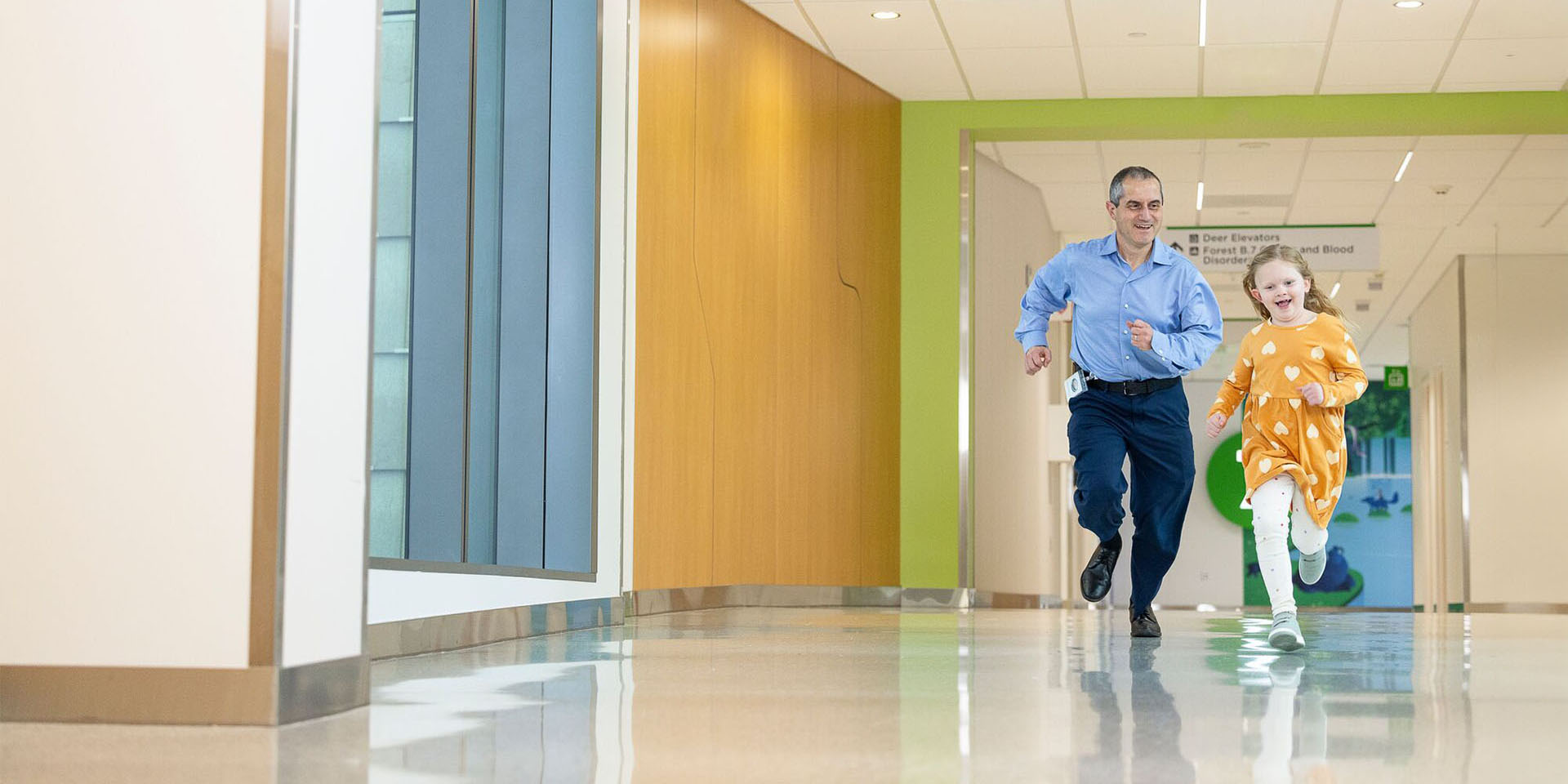 A Seattle Children's provider runs down a hallway with a young girl