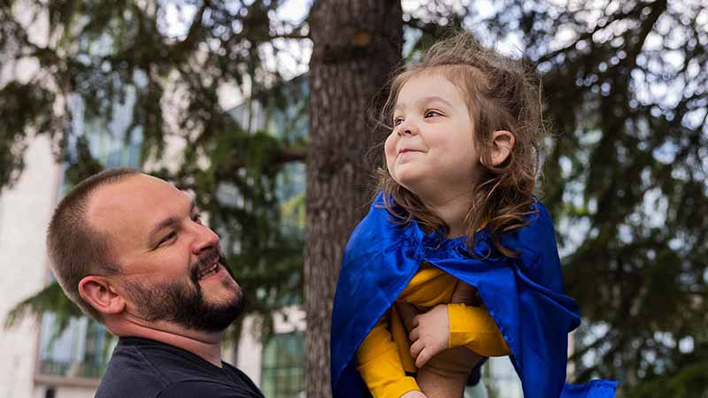 A girl is lifted in the air by her father