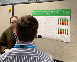 A woman in front of a poster talks to a man