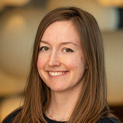 A headshot of a woman with long brown hair smiling at the camera