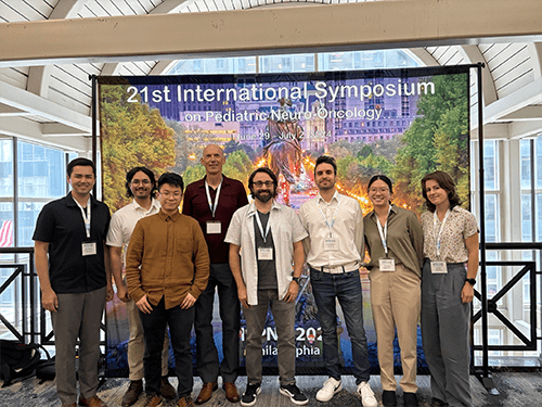 Dr. Vitanza and team in front of a symposium banner